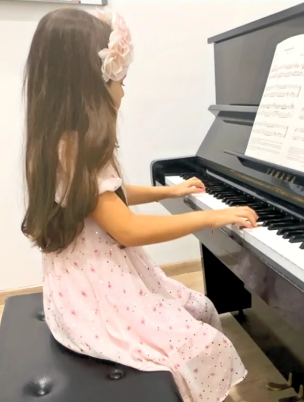 Little girl playing piano in a classroom at Oohlala Music School, highlighting piano lessons or piano classes in Dubai.