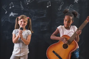 Two young girls, one holding a guitar and the other holding a microphone, as they start music lessons.