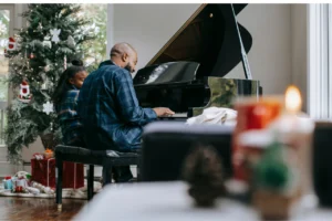 Christmas piano songs - man playing piano with daughter.