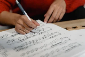 Person writing on sheet music for piano improvisation